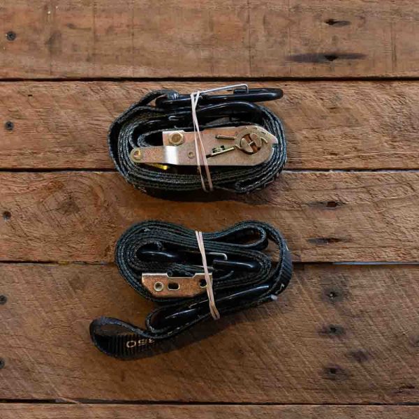 Black leather belts with metallic buckles on a wooden background.