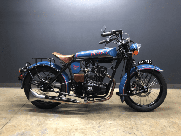 Blue and black Janus motorcycle with chrome details parked indoors.