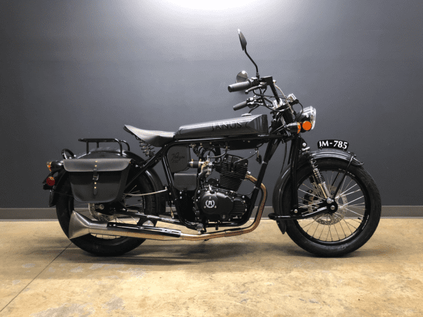 Black vintage motorcycle with side bag parked indoors.