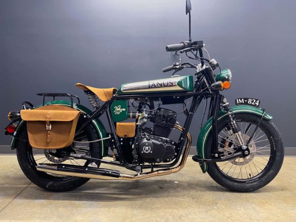 Classic green motorcycle with leather saddlebags on display.