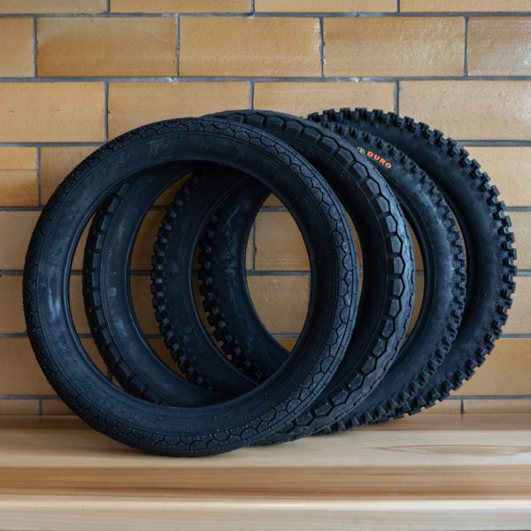 Three stacked bicycle tires against a brick wall.