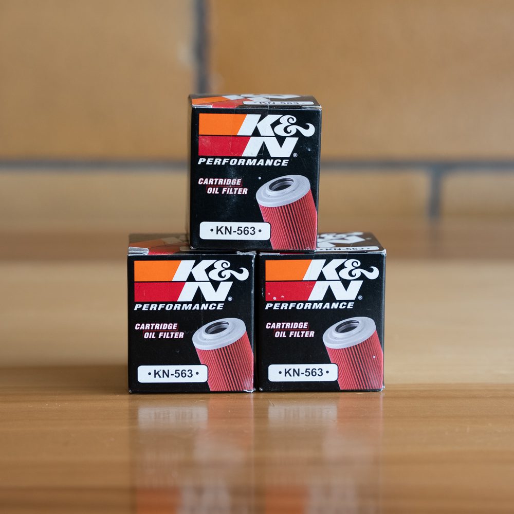 Three K&N Performance Cartridge Oil Filter boxes stacked on a table with clear branding.