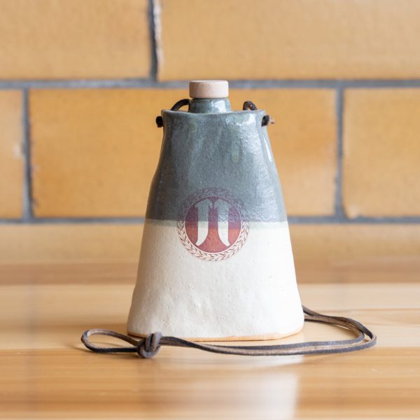 Ceramic cowbell on wooden table with brick wall background.