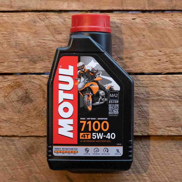 Bottle of Motul 7100 4T 5W-40 synthetic motorcycle oil on a wooden surface.