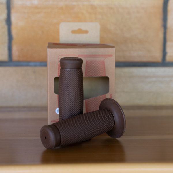 Brown bicycle handlebar grips on a wooden table with packaging in the background.