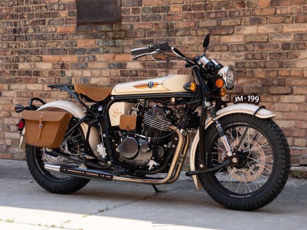 Vintage motorcycle parked by a brick wall with leather saddlebags.