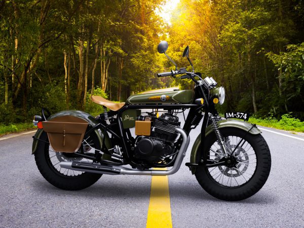 Classic green motorcycle parked on a forest road at sunset.