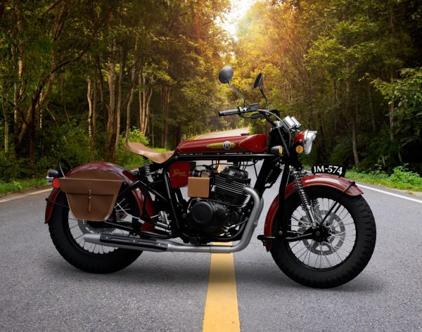 Classic red motorcycle parked on a forest-lined road at sunset.