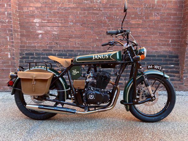 Classic Janus motorcycle parked against a brick wall.