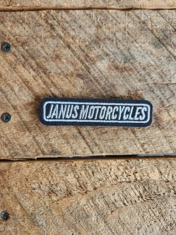 Janus Motorcycles patch on wooden background.