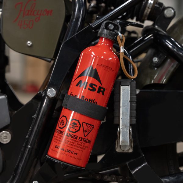 Red MSR fuel bottle attached to a black Halcyon 450 motorcycle.