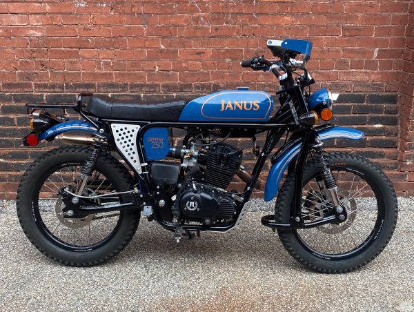 Blue JANUS Gryffin 250 motorcycle parked beside a brick wall.